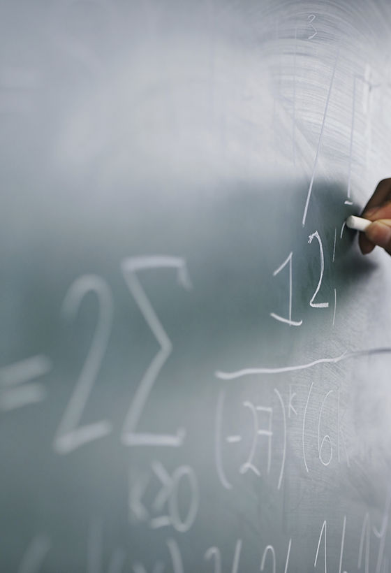 Teacher Writing a Formula on a Blackboard