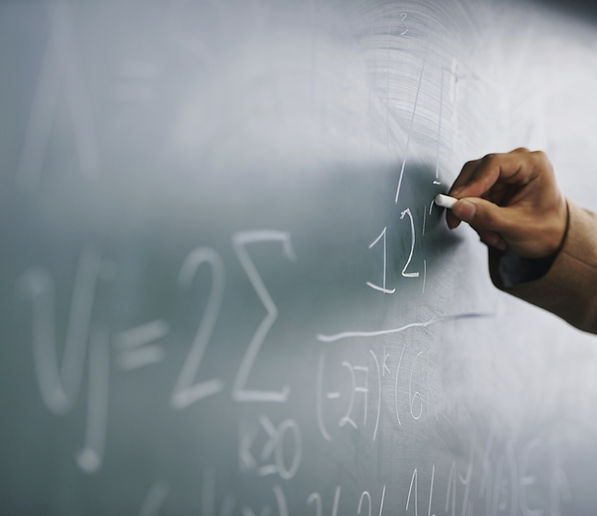 Teacher Writing a Formula on a Blackboard
