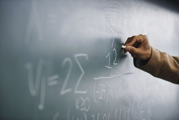 Teacher Writing a Formula on a Blackboard