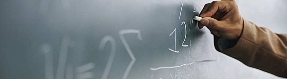 Teacher Writing a Formula on a Blackboard