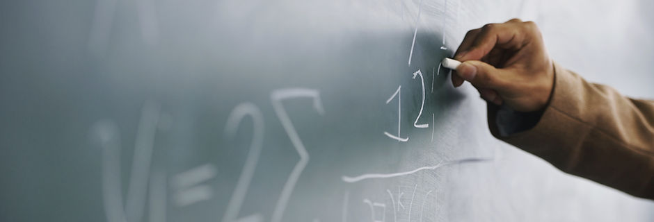 Teacher Writing a Formula on a Blackboard