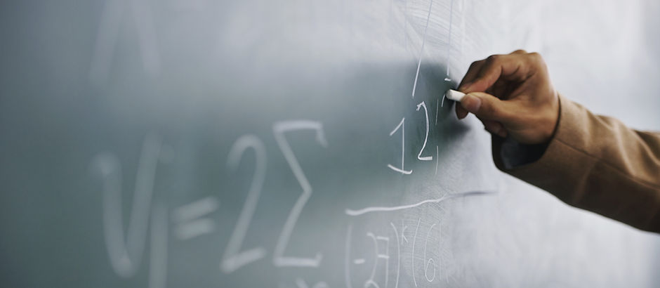 Teacher Writing a Formula on a Blackboard