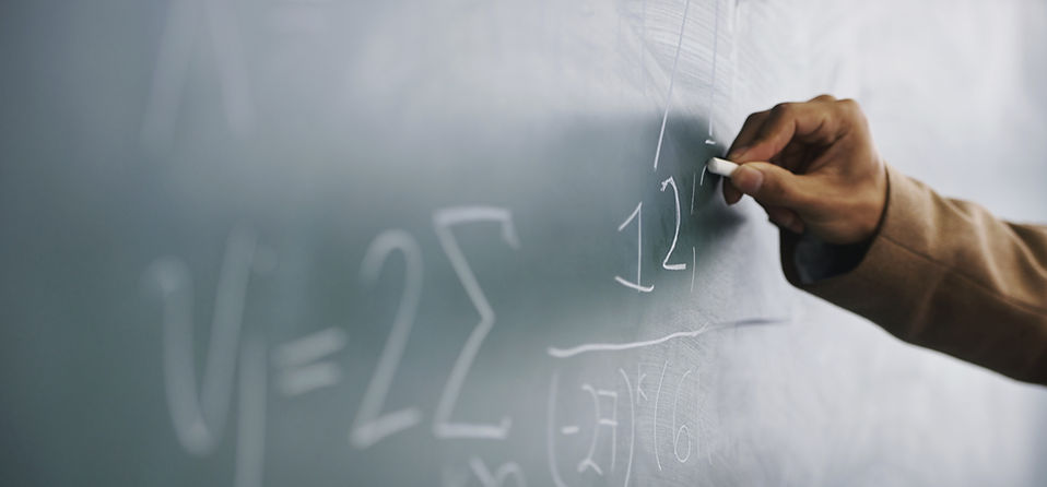 Teacher Writing a Formula on a Blackboard