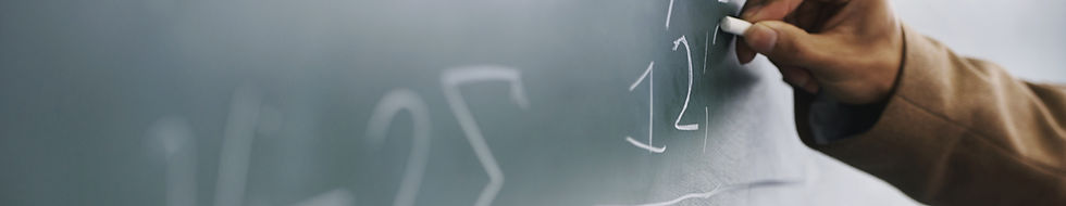 Teacher Writing a Formula on a Blackboard