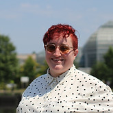 Abby, a white nonbinary person with red hair wearing sunglasses
