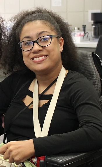 A woman with black hair and glasses smiling at the camera.