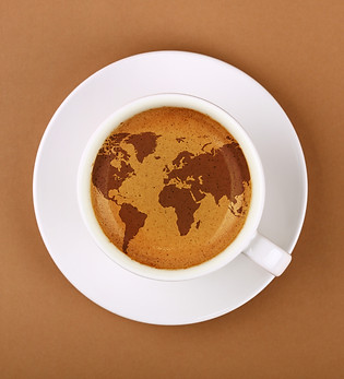 Close up white cup on saucer, full of espresso coffee with  map on froth crema, over backg