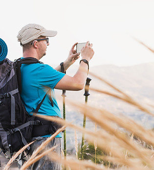 A hiker, adult, male, Caucasian, with a backpack, mat, poles, dressed in a blue T-shirt, c