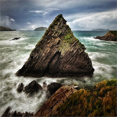 Large triangular rock surrounded by stormy sea in The Dingle, West Coast of Ireland