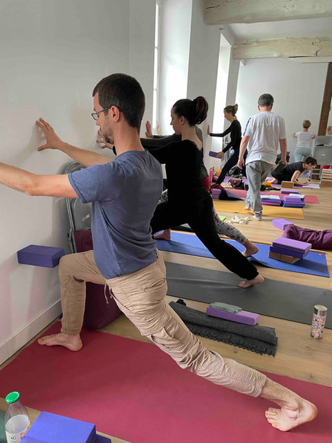 5 pratiquants préparant Virabhadrasana 1 avec une brique de Yoga contre un mur