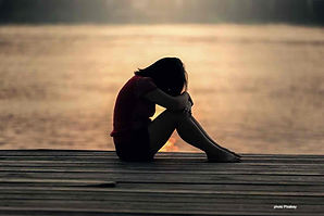 Une jeune femme triste est assise en borde de mer