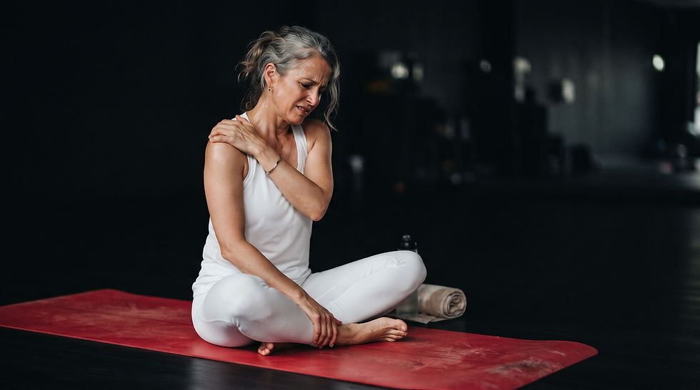 Pratiquante de yoga d'une cinquantaine d'années ressentant une douleur à l'épaule pendant une posture sur tapis, illustrant les troubles musculo-squelettiques et l'importance de la yogathérapie posturale.