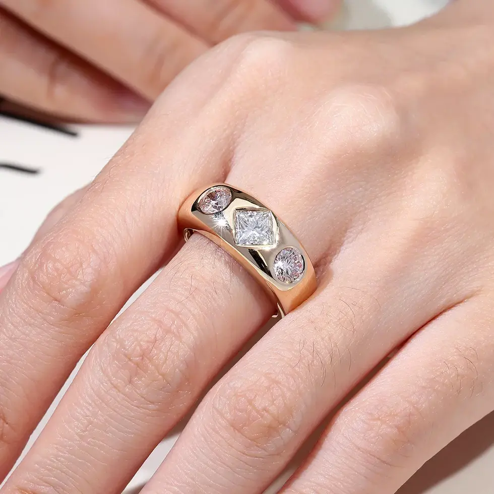 Bezel-set three-stone diamond band worn on hand, princess and round cut