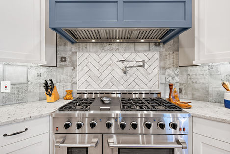 Range and patterned stone backsplash in the French Elegance kitchen.
