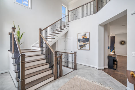 Double-height entry with a wood staircase, metal balustrade and console table.