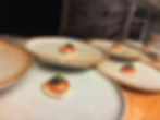 Plates with blinis topped with salmon and caviar on a wooden counter. Background features a black-and-white photo of a beach.