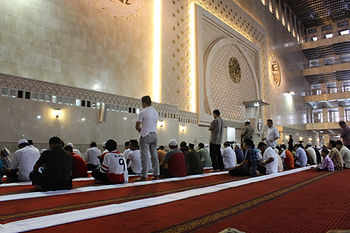 camide cami halısı üzerinde dua eden insanlar