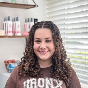 Natural highlighted brunette below the shoulder curly haircut and styled for defined curls