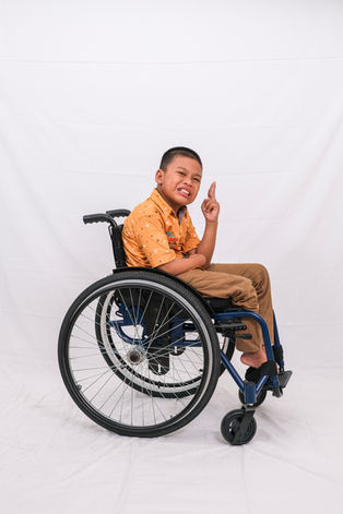 Young boy in wheelchair points up; Adaptive Wheelchair program in action.