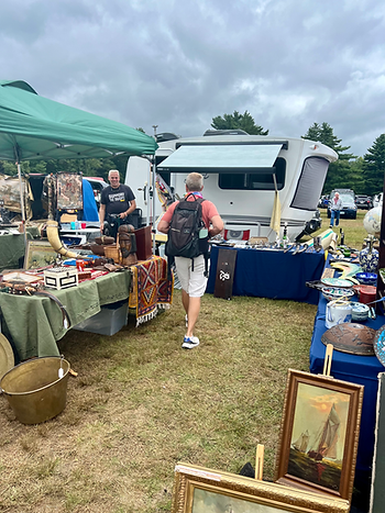 A Intech Sol Dawn Camper at the back of a spot where there is an array of antiques for sale 