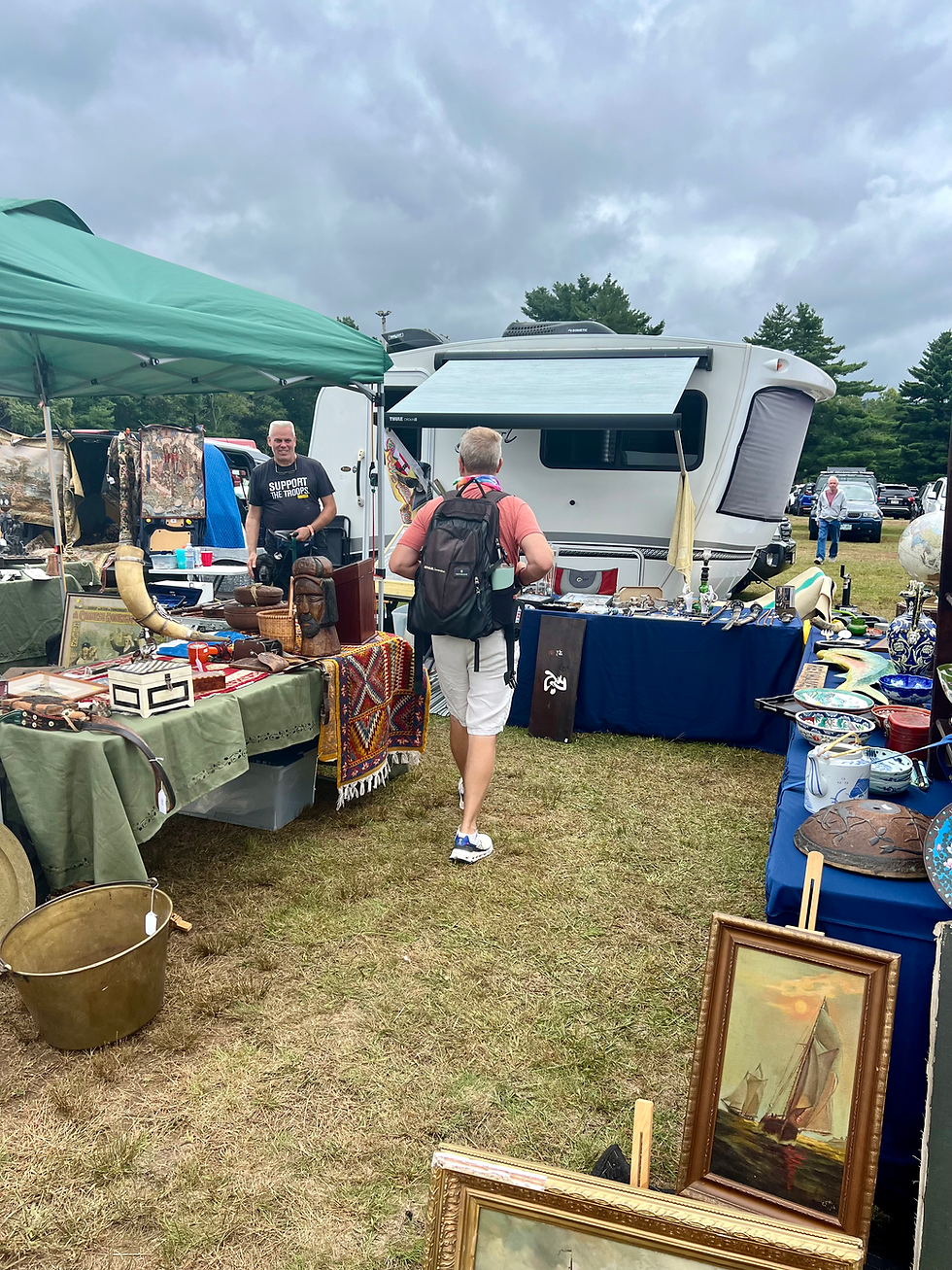 A Intech Sol Dawn Camper at the back of a spot where there is an array of antiques for sale