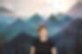 Photo of Jen smiling in front a background screen print of mountains and birds flying