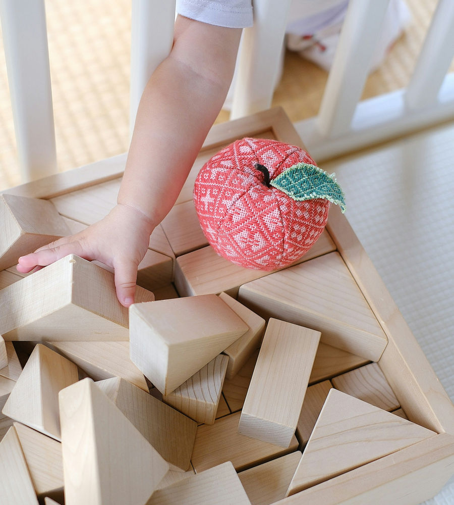 A child's hand building with natural wooden blocks