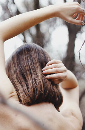 A portrait photograph of a female with her back facing the camera in a graceful mid movement position