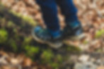 A young child walking on a log in the woods.
