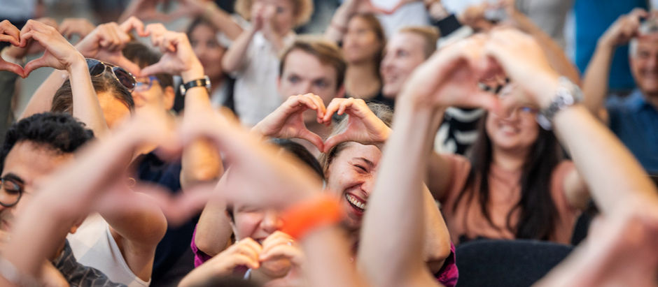 Audience members holding their hands in a heart shape