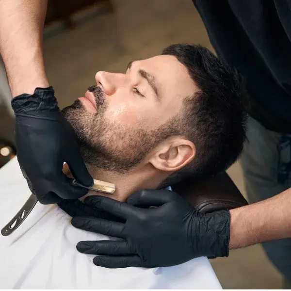 Un homme se fait tailler la barbe par un barbier dans un salon de coiffure.