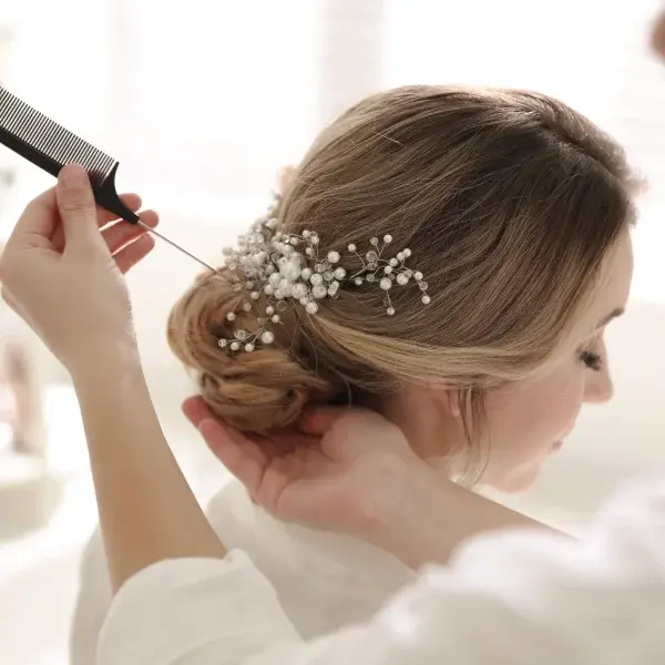 Une femme se fait coiffer avec un peigne pour une coiffure de mariage élégante et raffinée.