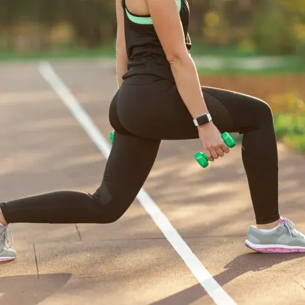 A woman performs a squat while holding two dumbbells, demonstrating strength training and mobility massage techniques.