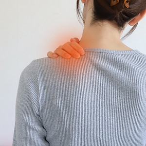 肩こり悩む女性が痛そうに肩を抑えている