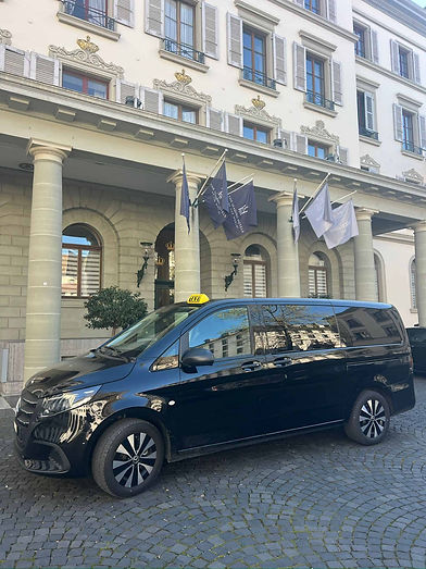 Un van Mercedes taxi qui stationne devant un hôtel.