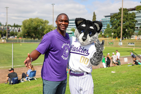 Norris Frederick smiles with Dubs, the University of Washington mascot, during the Dawgs vs. Cougs celebrity softball game at the Junior Little League World Series.