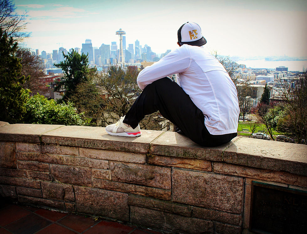 Norris Frederick sitting on a stone wall overlooking the Seattle skyline and Space Needle, reflecting on life after sports and the athlete’s journey beyond competition.