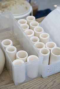 Unglazed ceramic guitar slides arranged in rows.