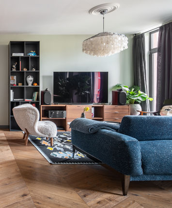 Сучасна вітальня з дерев'яною підлогою, стильними меблями та живими рослинами.