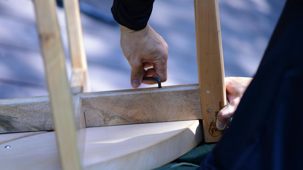 Close-up of a person assembling wooden furniture with an Allen wrench on a sunny day.