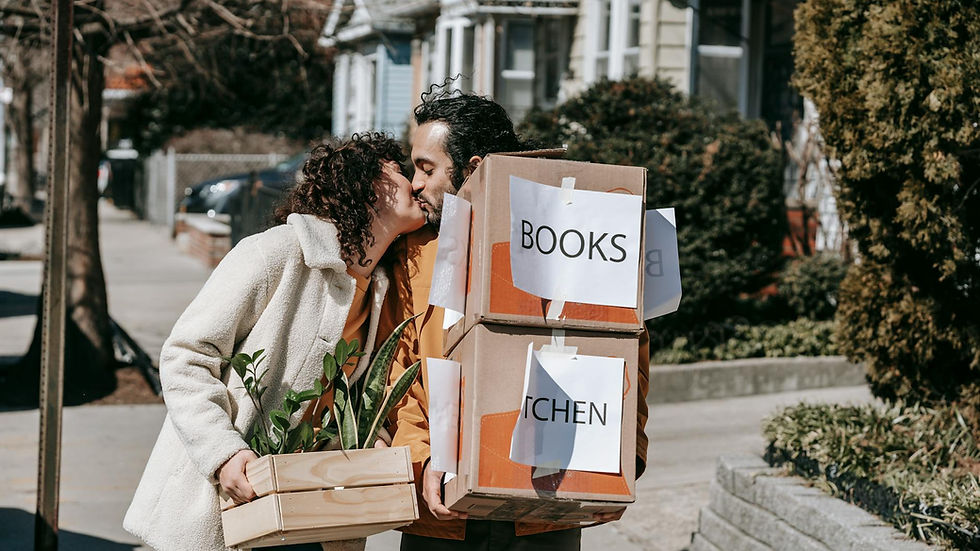 Joyful couple sharing a moment while moving boxes in sunny urban area. Love and happiness depicted outdoors.