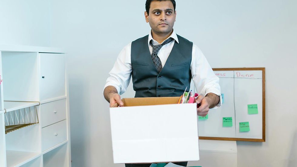 Professional man organizing office belongings in a cardboard box, preparing for transition.