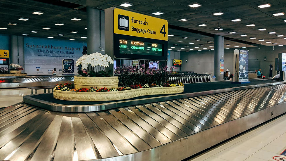 Modern baggage claim area at Suvarnabhumi Airport in Bangkok with luggage carousel and signage.
