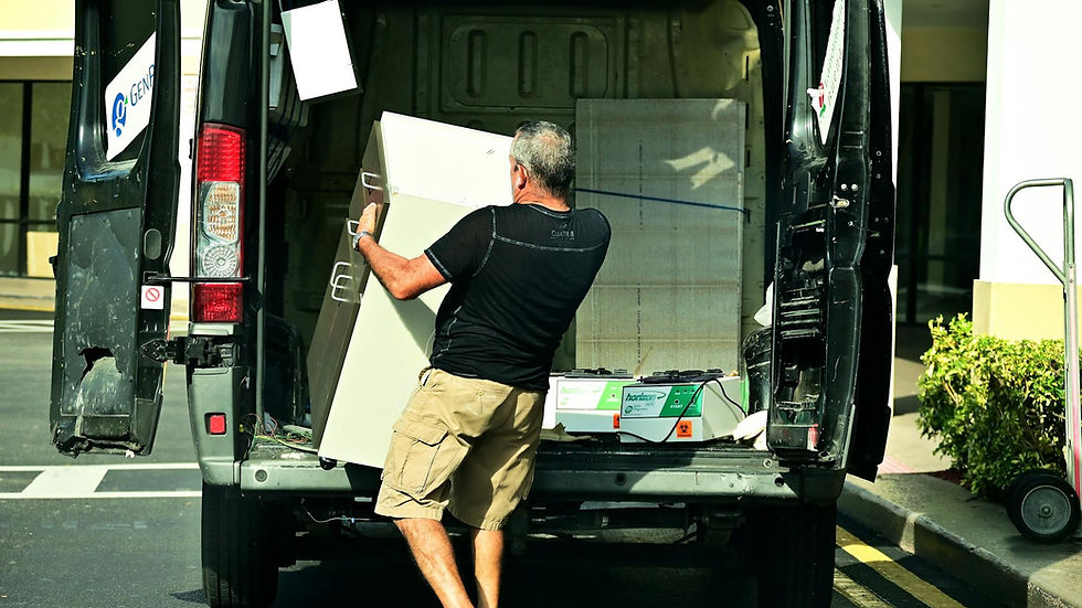 Adult man loading furniture into an open van in a parking lot, daytime setting.