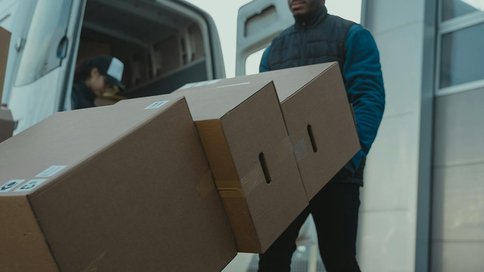 Delivery man carrying cardboard boxes from a van outside a modern building.