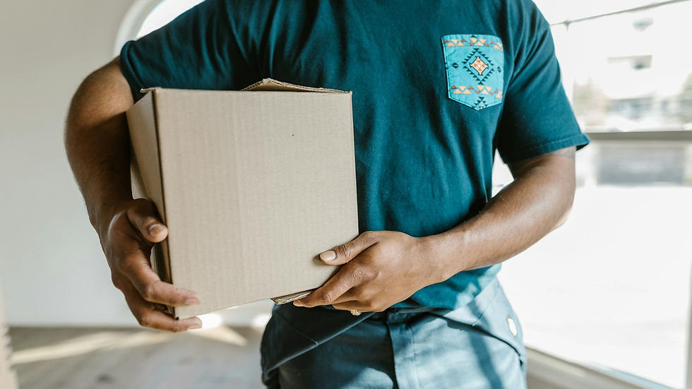 Close-up of a man holding a cardboard box in a bright room, symbolizing moving or delivery.