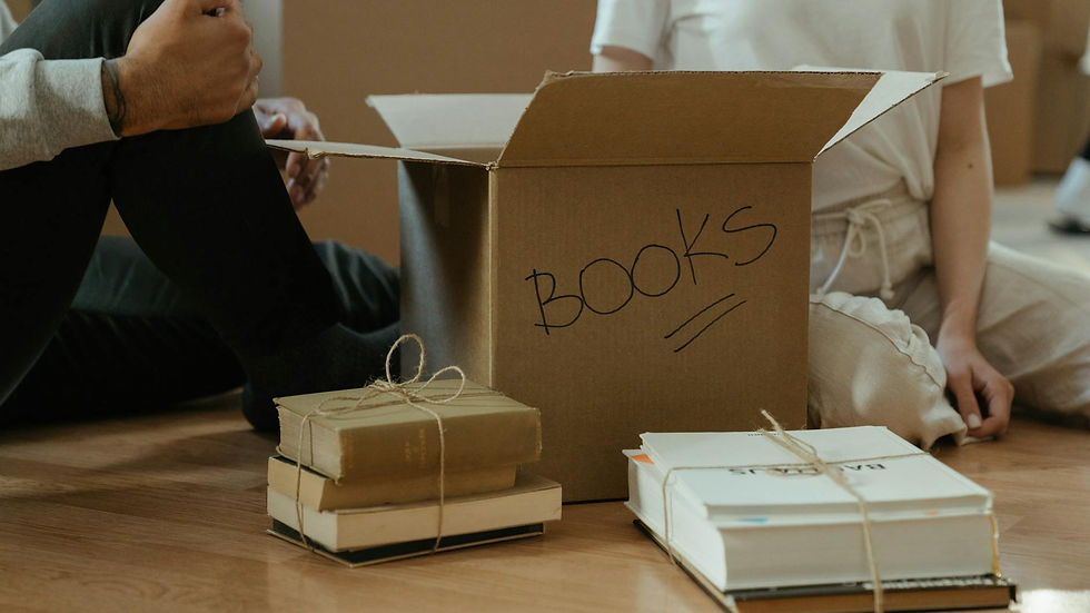 Person unpacking books from a cardboard box in a cozy home environment.