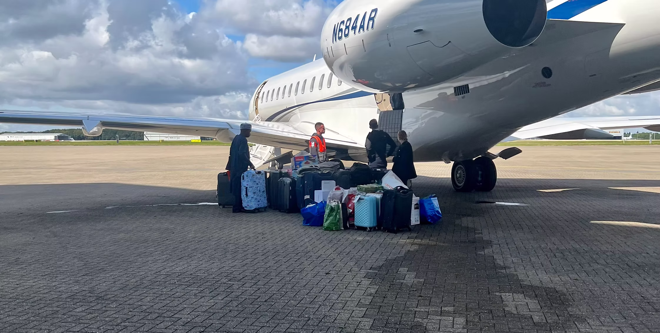 An Airport To Home porter courier unloading bags from the delivery truck holding about 60 suitcases into a private jet for a private client flying from a private hanger luggage transfer service