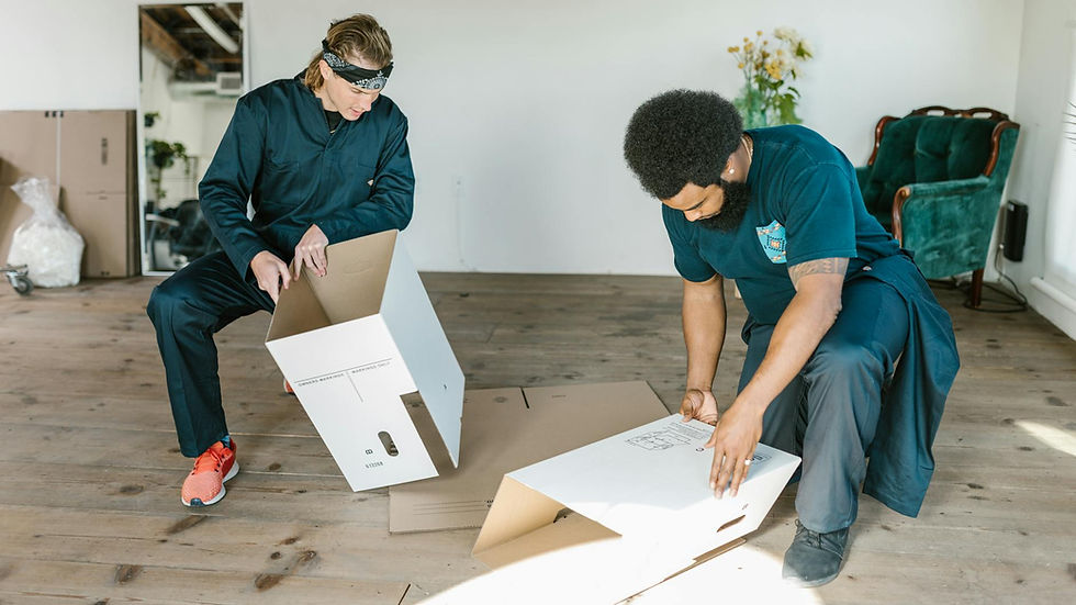 Two men assembling cardboard boxes indoors, preparing for moving.