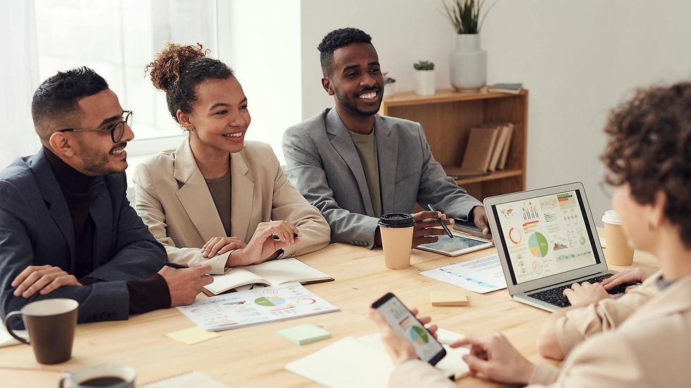Young professionals discussing work at a conference table with technology and documents.